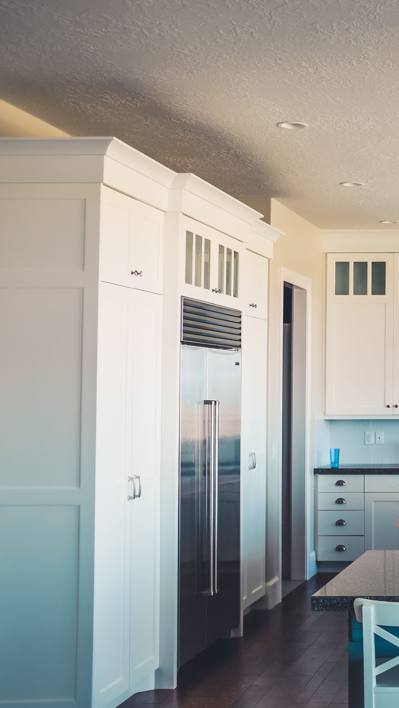 Stainless built-in refrigerator in a bright white kitchen